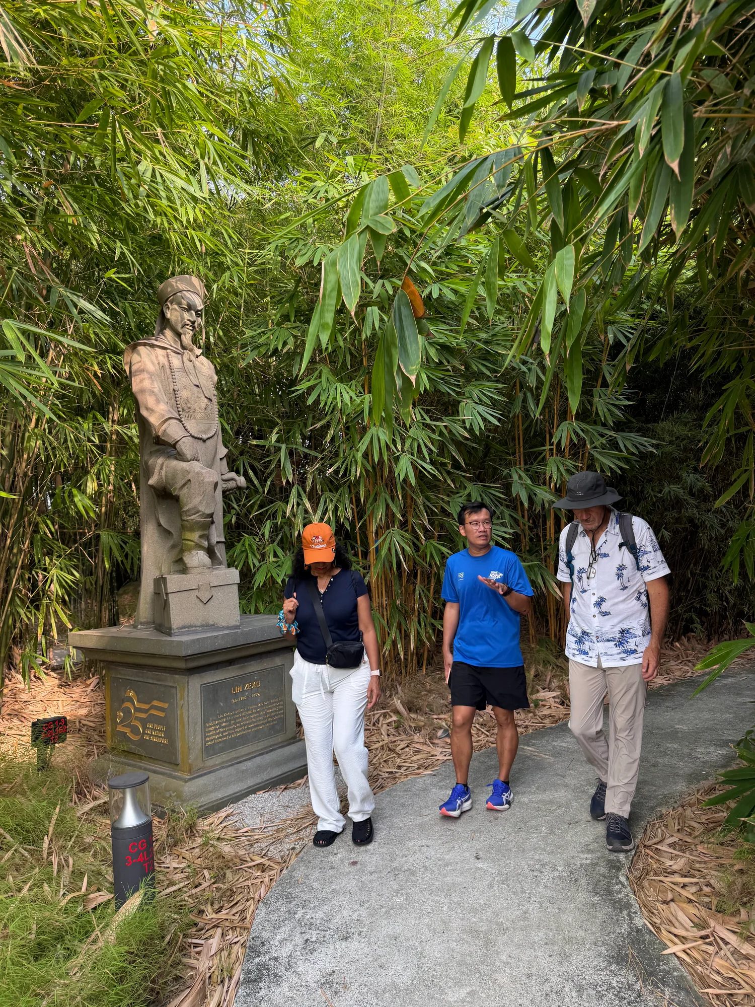 Tour guide leading guests past a historical statue on a bamboo path in the Chinese Garden