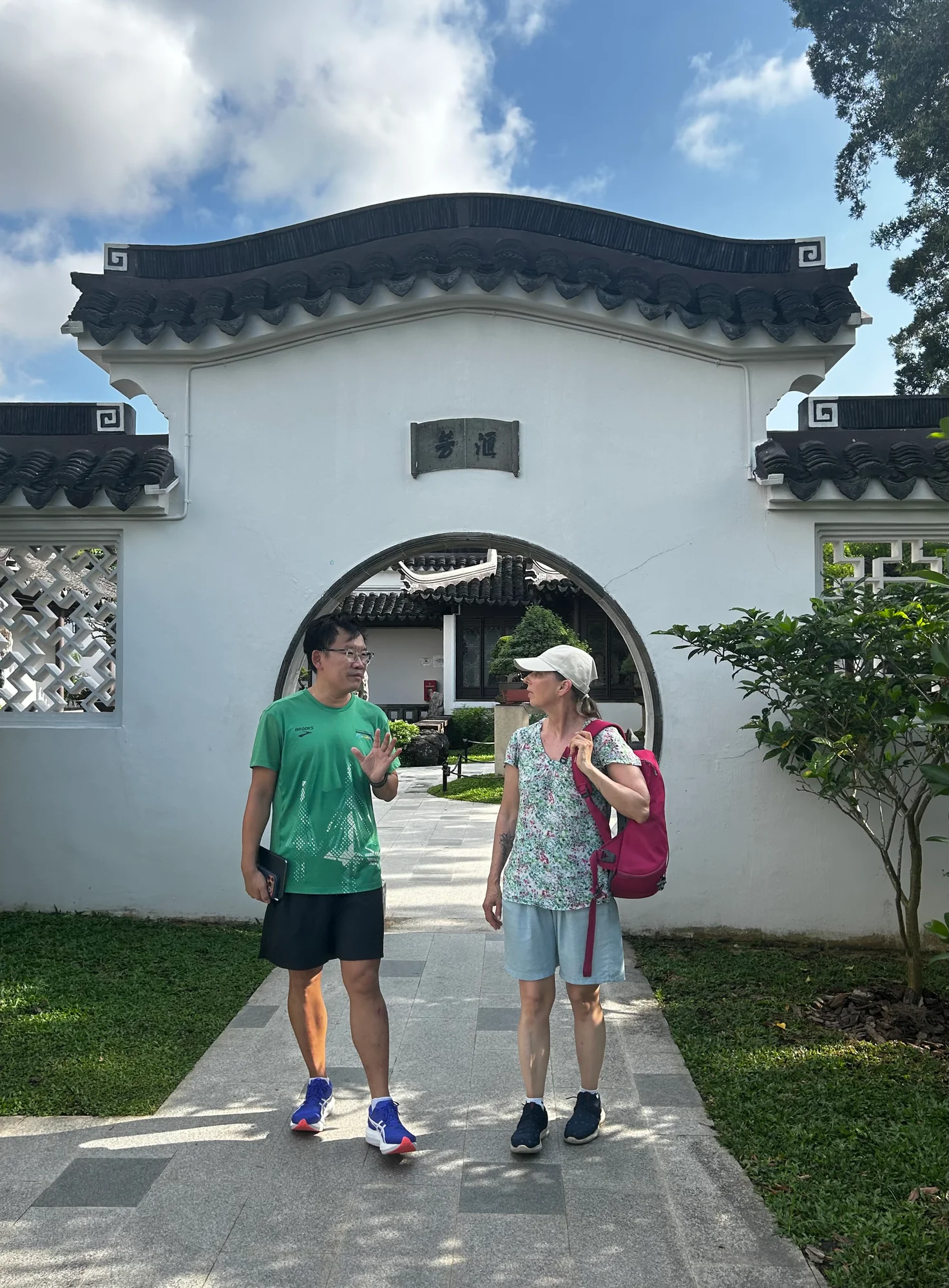Tour guide and guest walking through a moon gate in the Chinese Garden