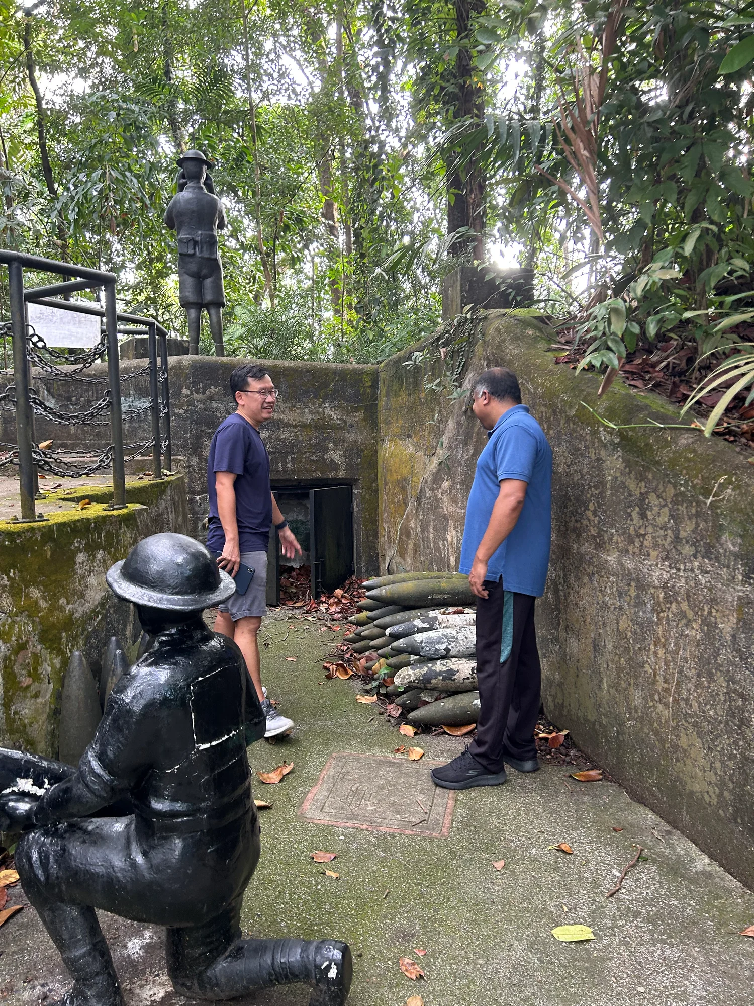 Tour guide and guest at a WWII gun emplacement with soldier statues and artillery shells at Labrador Nature Reserve