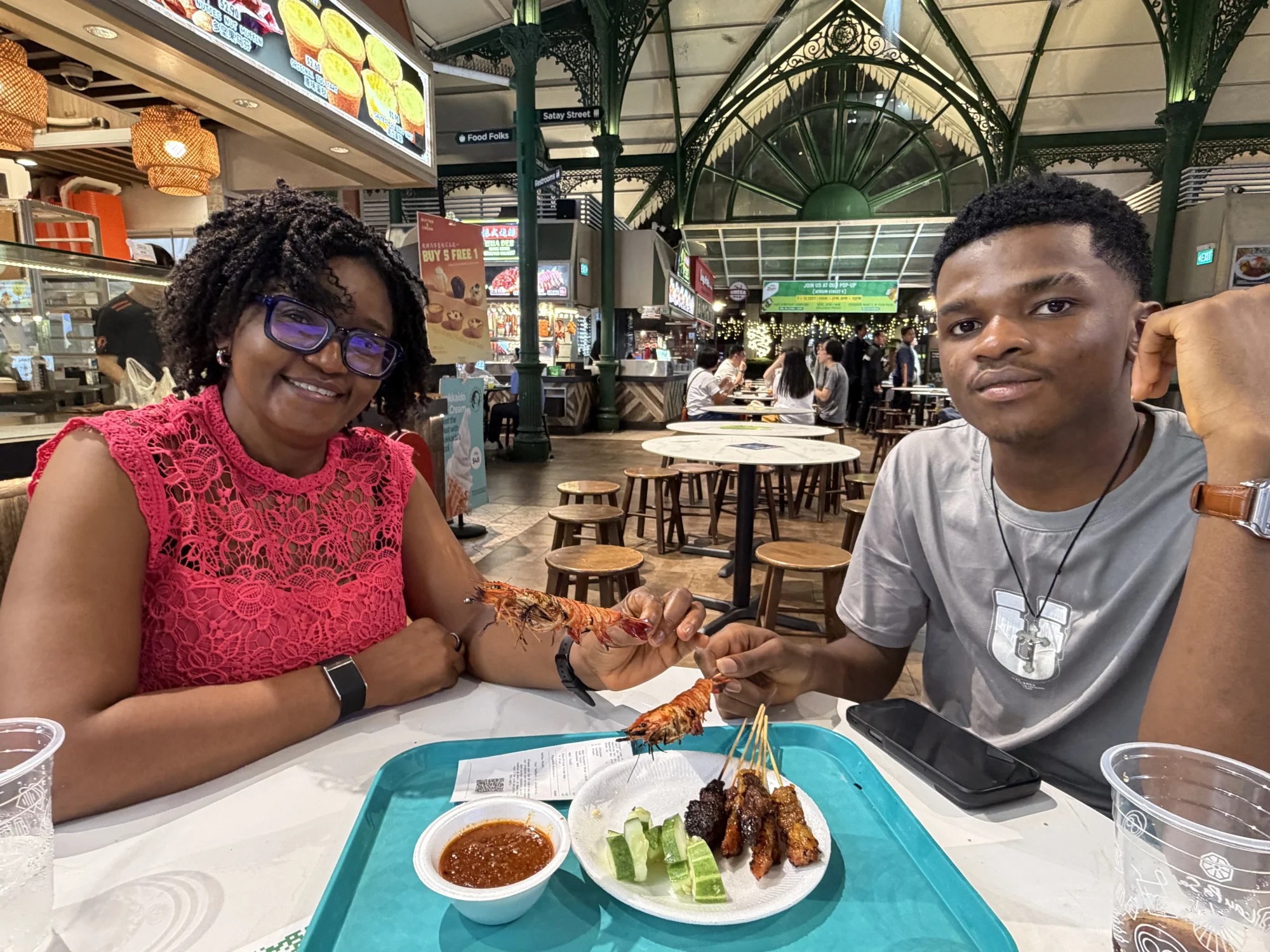 Walking tour guests enjoying satay and grilled prawns at Lau Pa Sat