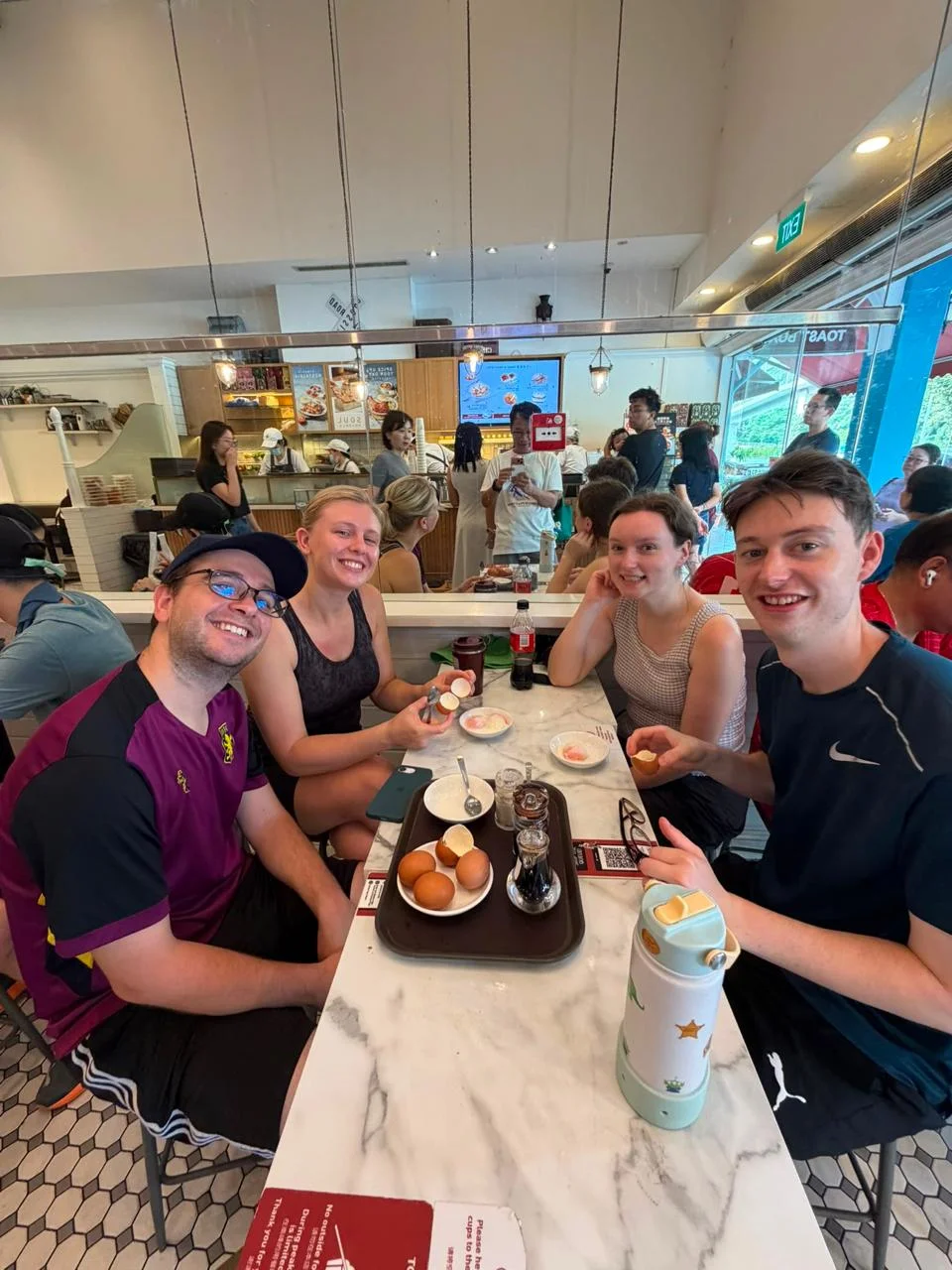 Walking tour guests sharing a local breakfast of kaya toast and soft-boiled eggs