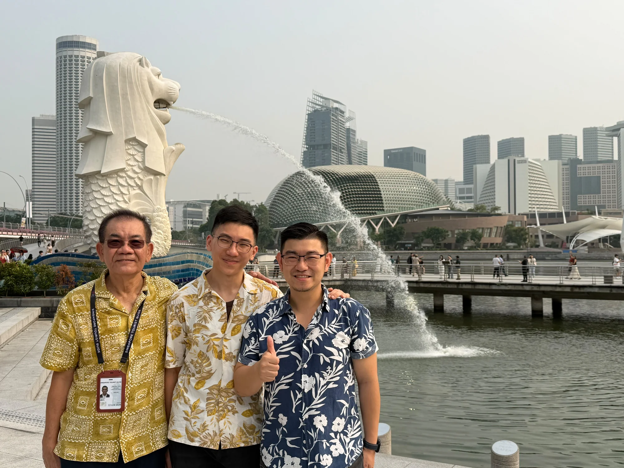 Tour guide and guests at the Merlion, with the Esplanade across Marina Bay